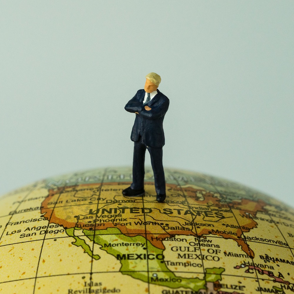 miniature people figure businessman standing on united states of america map on globe as world leader decision concept